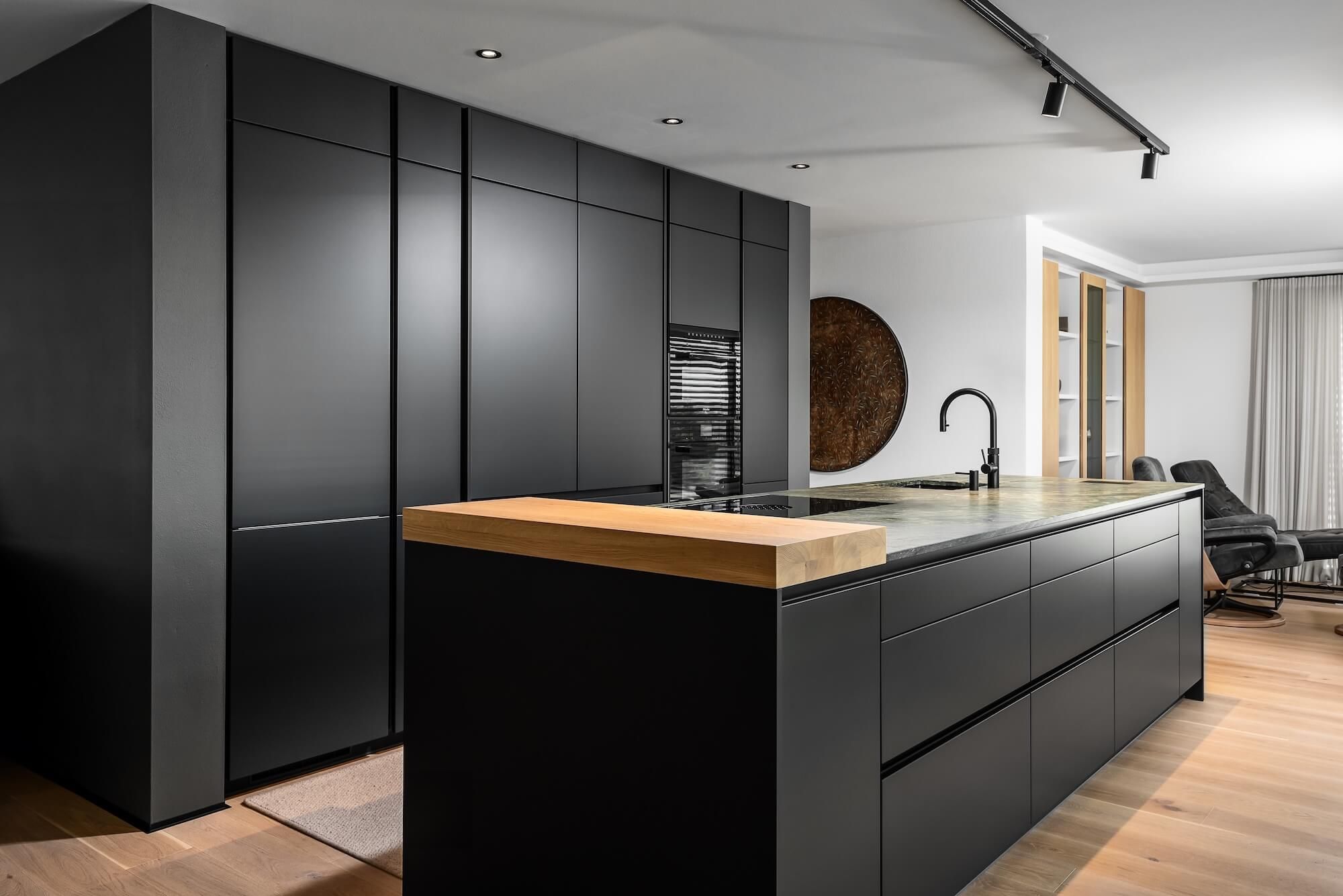 Moderne Anthrazit Küche mit einer Steinarbeitsplatte und einer massiven Bar in Eichenholz sorgen für einen ouristischen Charakter.