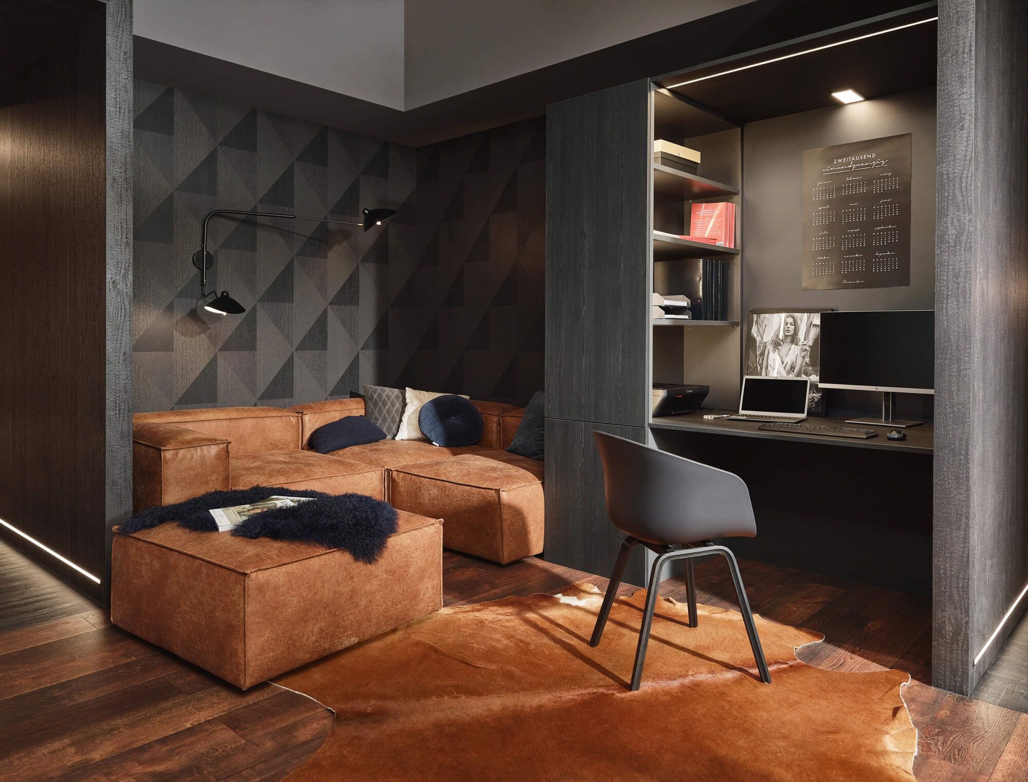 Stilvolles Wohnzimmer mit braunem Ledersofa, Home-Office-Arbeitsplatz und dunkler Wandverkleidung