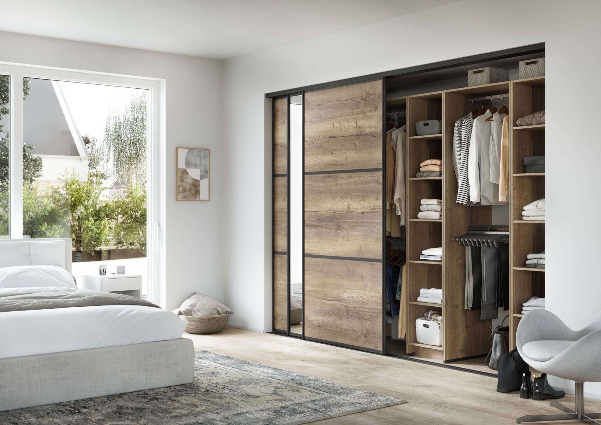 Helles Schlafzimmer mit maßgefertigtem Kleiderschrank aus warmen Holz. Spiegeltür vergrößert den Raum.