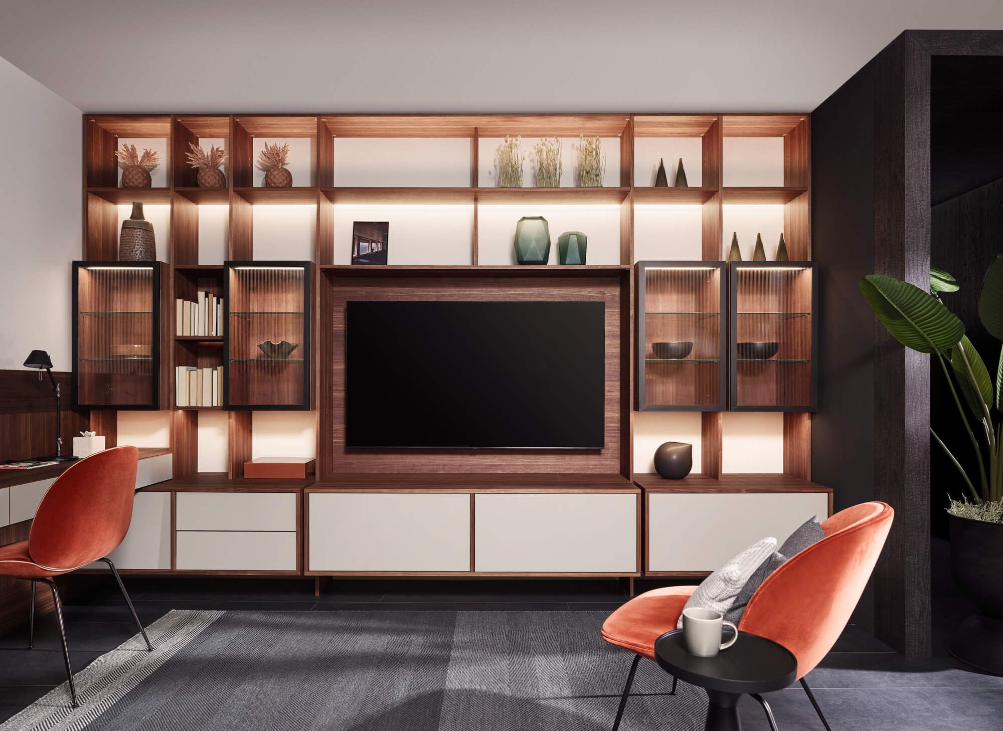 Modern eingerichtetes Wohnzimmer mit großer Wohnwand, Fernseher, Regalen und gemütlichen Sesseln