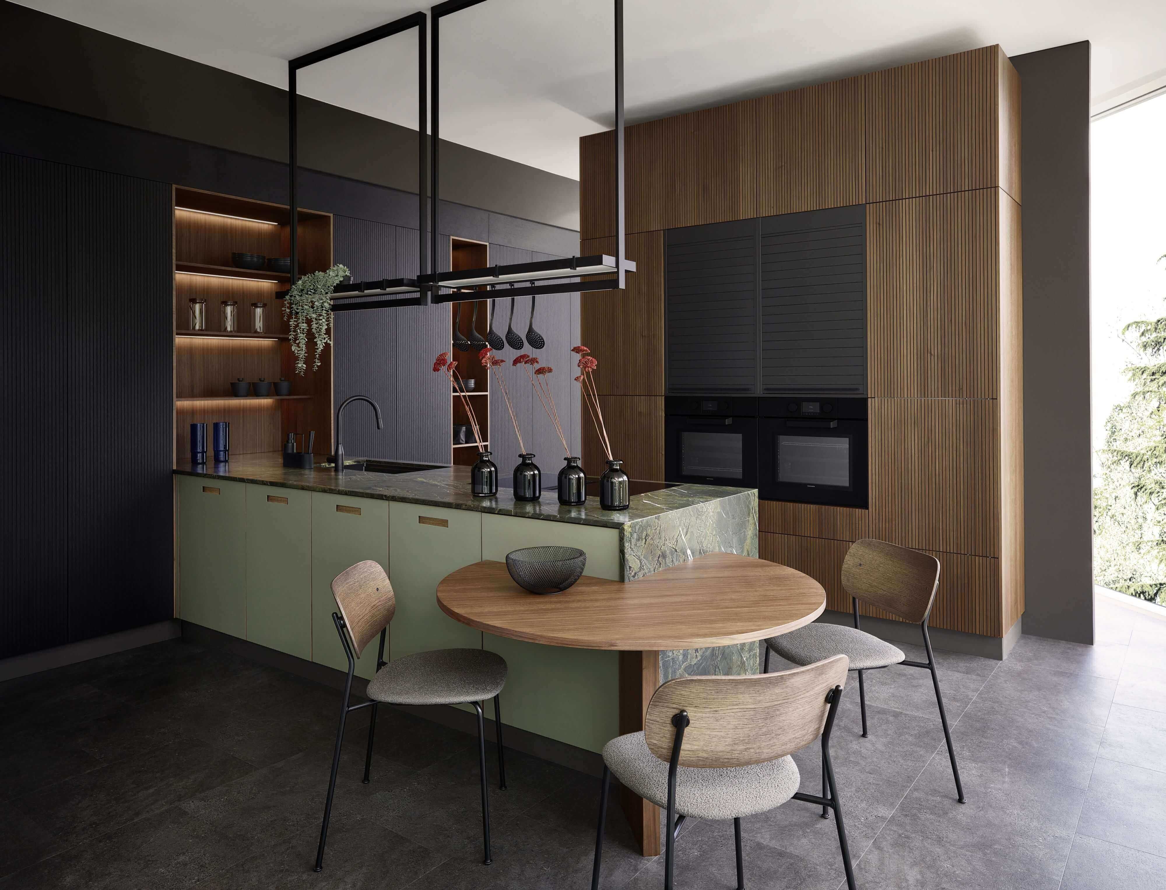 Moderne Küche mit grüner Granitarbeitsplatte, dunklen, grünen und warmen Holzfonten. Hochwertige Materialien, funktionale Stauraum und ein angegliederter runder Essbereich perfektionieren diese Küche.