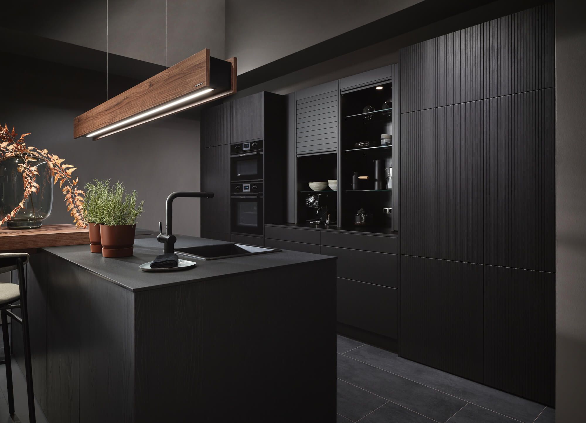 Elegante schwarze Küche mit Kücheninsel, Holzleuchte und stilvoller Dekoration