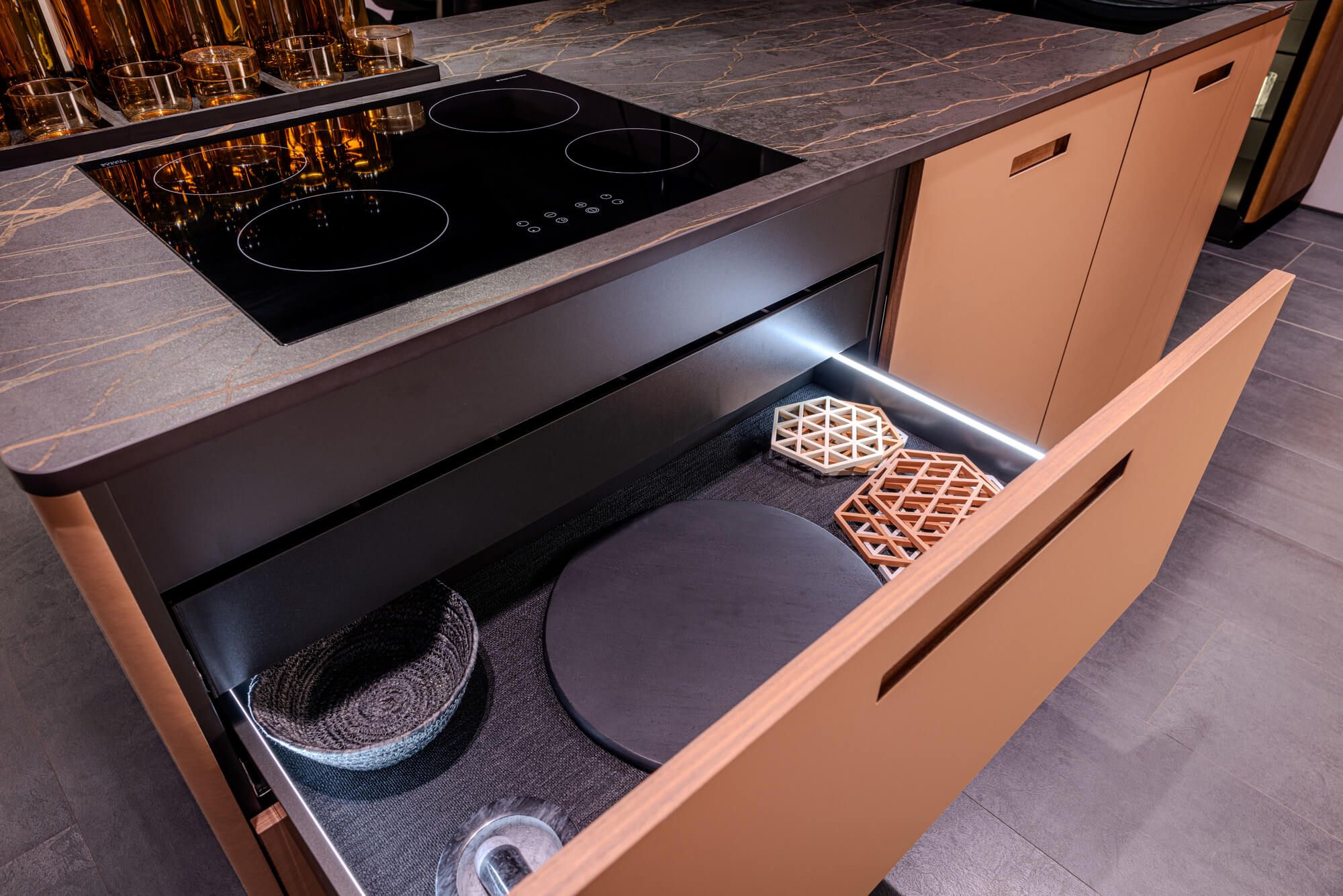 Geöffnete Schublade in moderner Küche mit Induktionskochfeld und stilvollem Zubehör