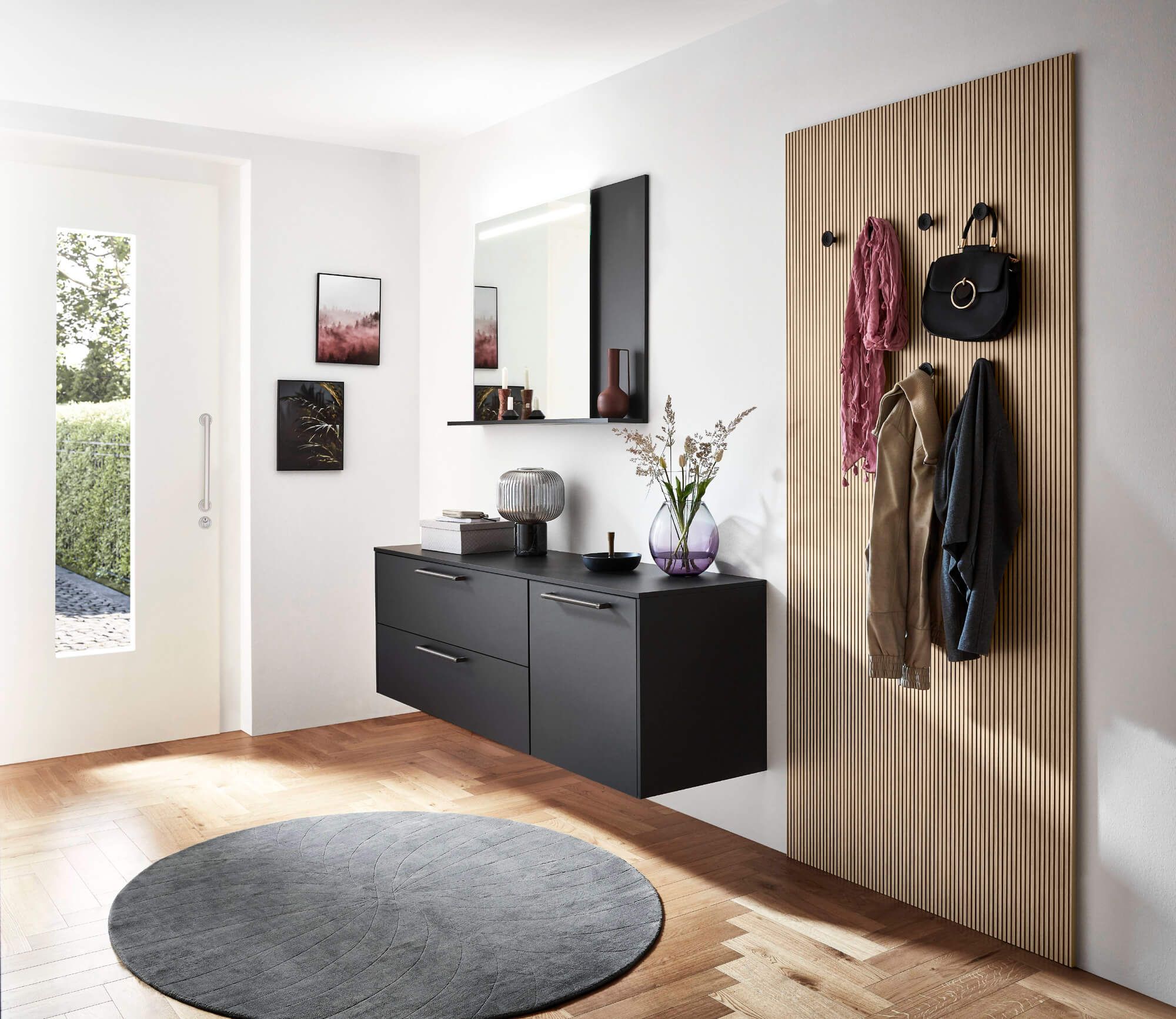 Heller Vorraum mit schwarzen Hängekommoden, Holz-Garderobenwand, Wandspiegel und dekorativen Accessoires