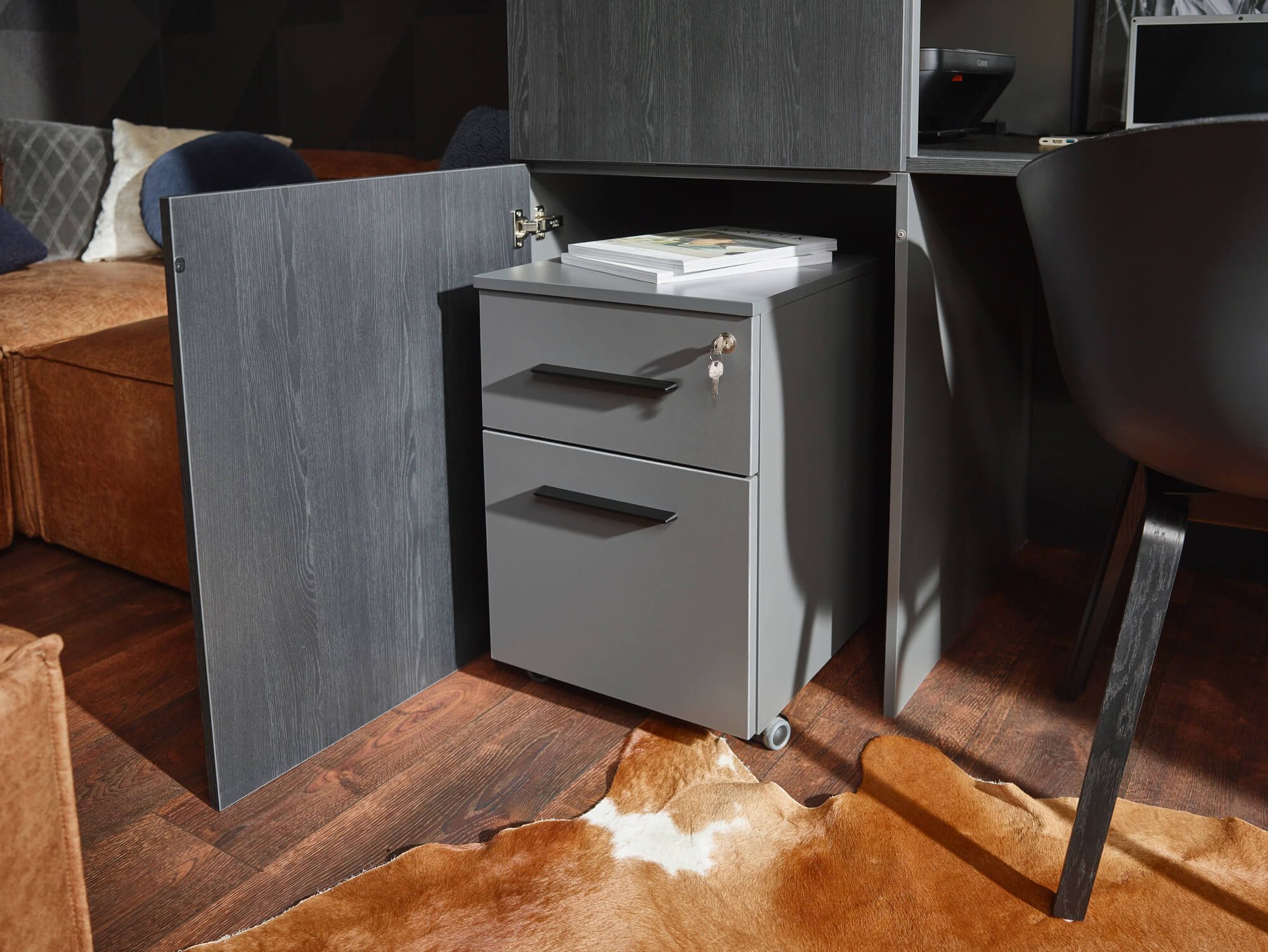 Grauer Rollcontainer mit zwei Schubladen in einem offenen Schrank im modernen Büro